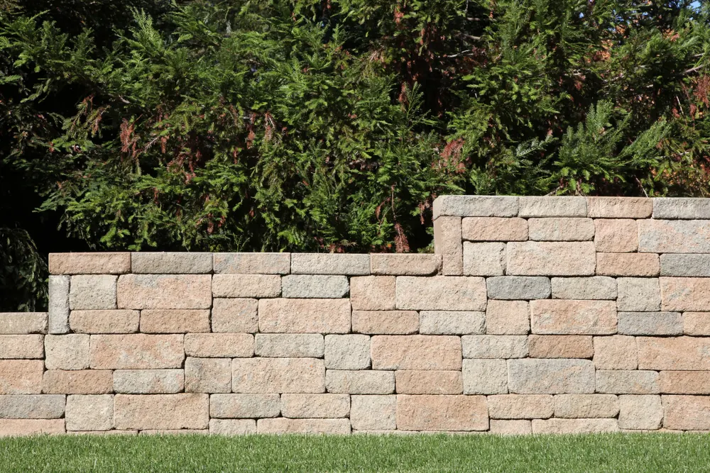 Stacked concrete block retaining wall in a landscaped yard in Baldwin NY — Nassau County Concrete